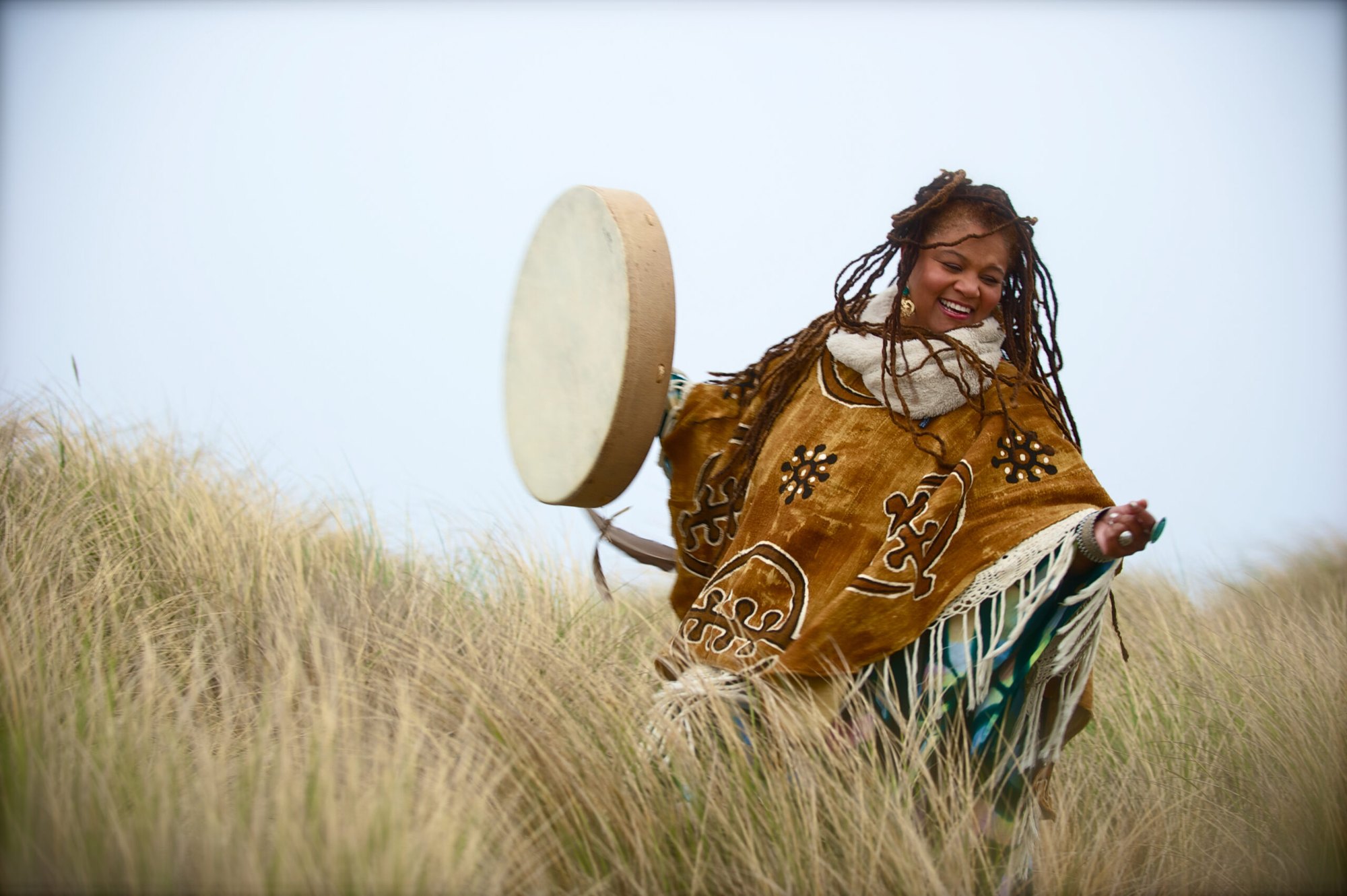 Amikaeyla mid-leap with a frame drum, holding rhythm in motion